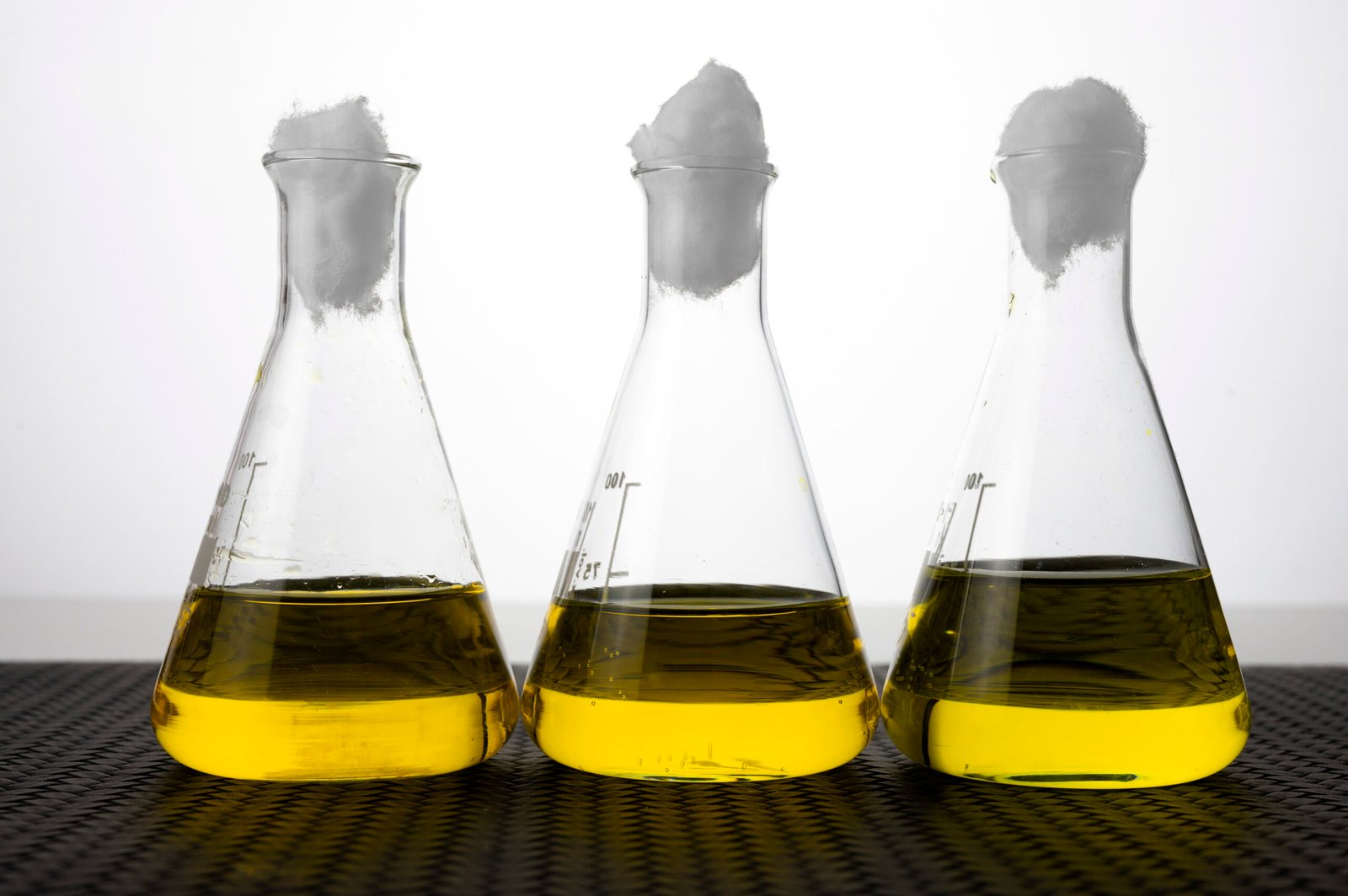 Three laboratory flasks containing golden liquid.